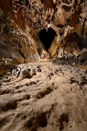 Cueva Canuela (Cantabrie, Espagne) - Galerie avec gours corrodés au sol et galerie en forme de coeur en fond (personnage lointain en arrière plan).(SP-26-1022 )